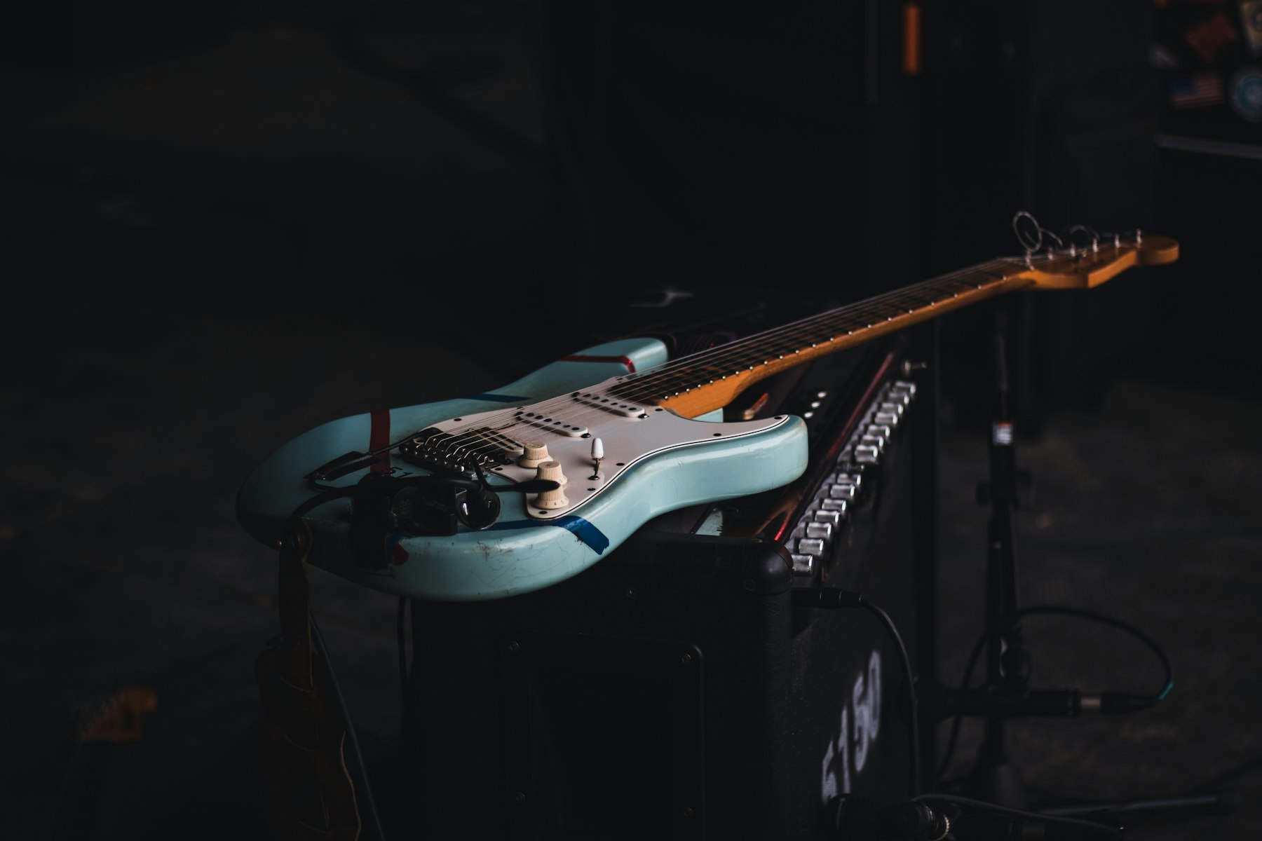 A seafoam electric guitar resting on a stage amplifier