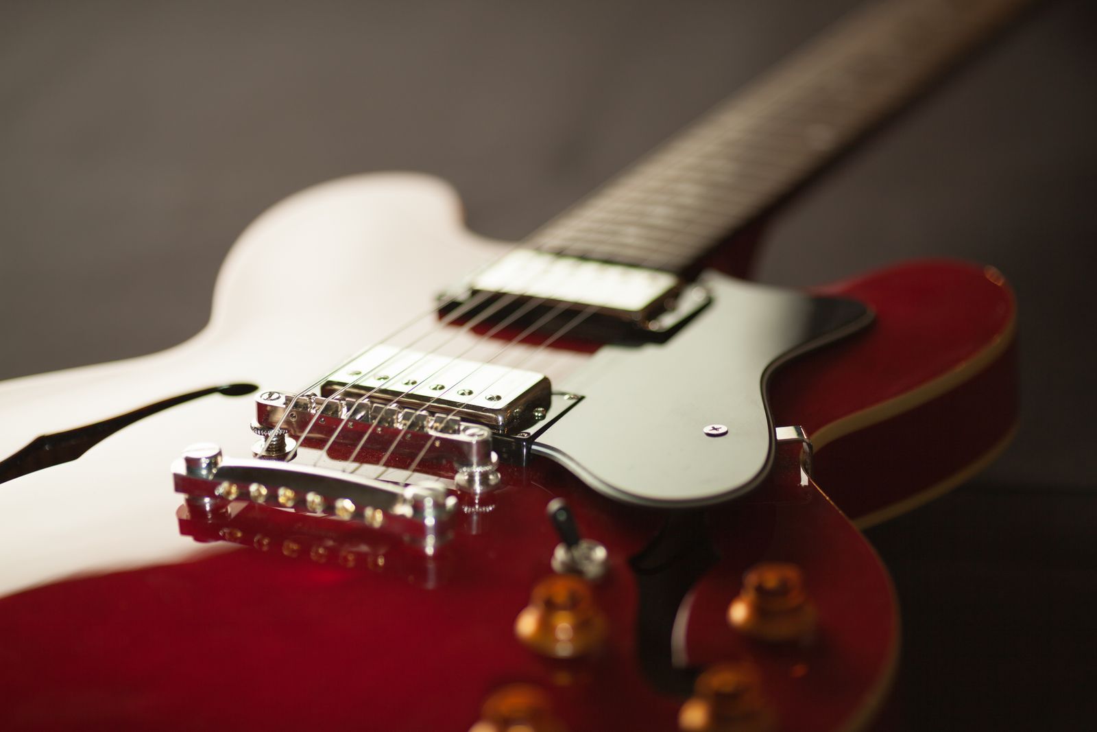 Detail of a cherry-red hollow-body electric guitar